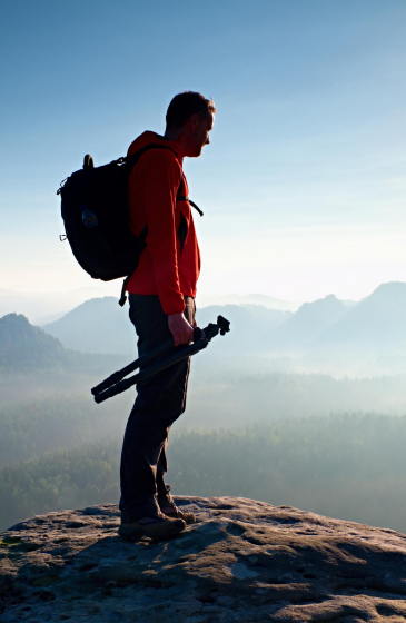 traveler standing on a mountain with backpack enjoying scenic nature view